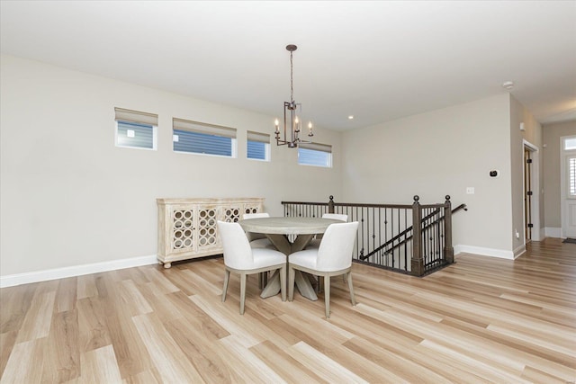 dining space featuring light wood-type flooring and an inviting chandelier