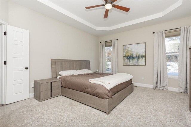 carpeted bedroom with ceiling fan and a raised ceiling