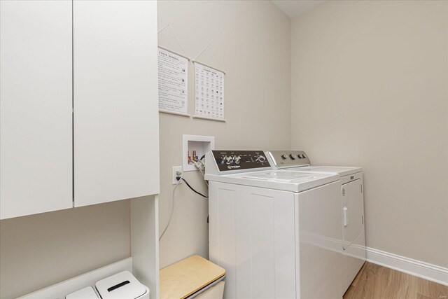 washroom with washer and dryer, cabinets, and light hardwood / wood-style flooring