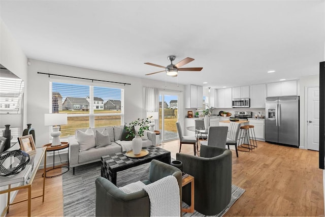 living room with ceiling fan and light hardwood / wood-style flooring