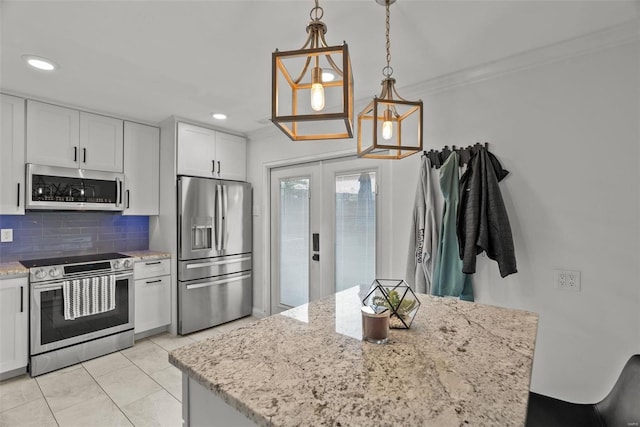 kitchen featuring backsplash, white cabinets, light tile patterned floors, appliances with stainless steel finishes, and decorative light fixtures