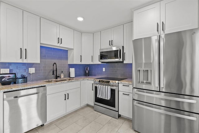 kitchen with sink, white cabinets, light tile patterned flooring, and appliances with stainless steel finishes