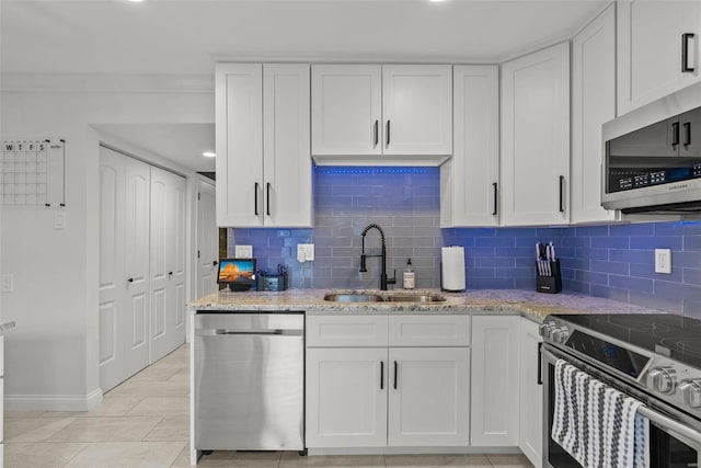 kitchen with white cabinets, stainless steel appliances, light stone countertops, and sink