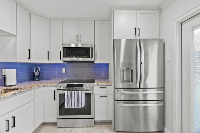 kitchen featuring light stone countertops, backsplash, stainless steel appliances, and white cabinetry