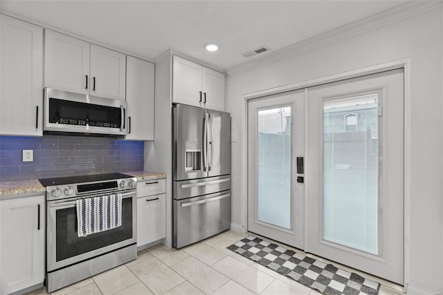 kitchen featuring light tile patterned floors, backsplash, appliances with stainless steel finishes, white cabinets, and ornamental molding