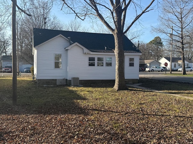 view of side of home with central AC unit and a lawn