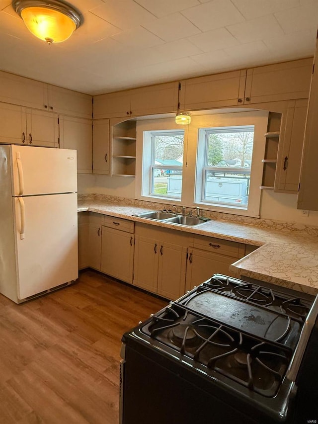 kitchen with black range, white refrigerator, sink, hanging light fixtures, and light hardwood / wood-style flooring