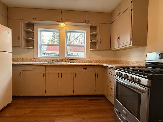 kitchen with sink, hanging light fixtures, white refrigerator, stainless steel range with gas stovetop, and light wood-type flooring