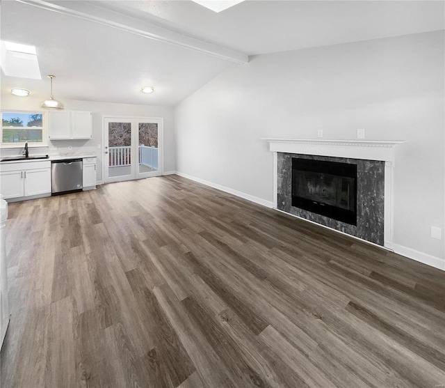 unfurnished living room with a high end fireplace, vaulted ceiling with beams, dark wood-type flooring, and sink