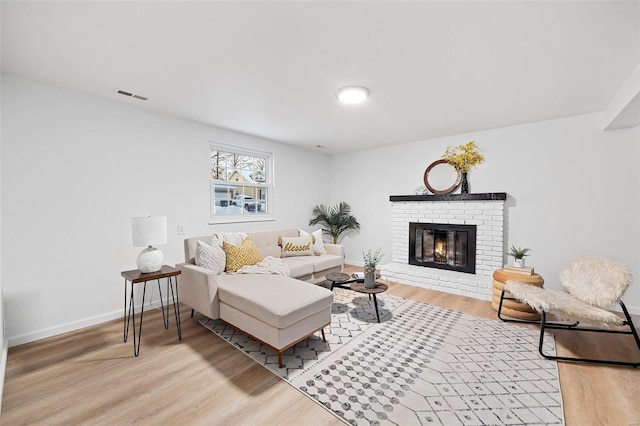 living room featuring a brick fireplace and light hardwood / wood-style floors