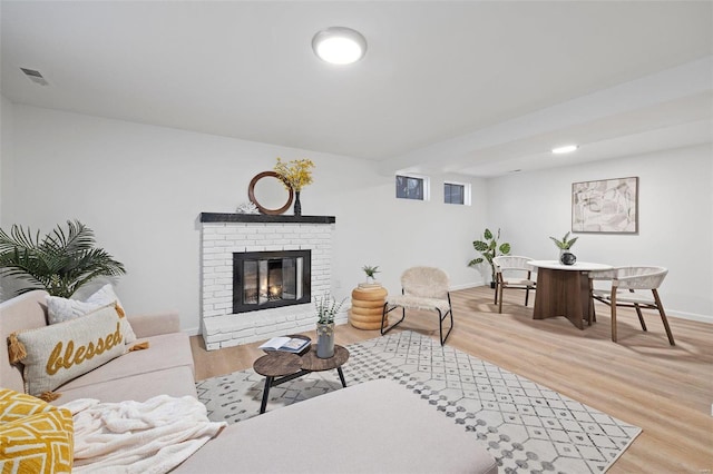 living room featuring a brick fireplace and hardwood / wood-style flooring