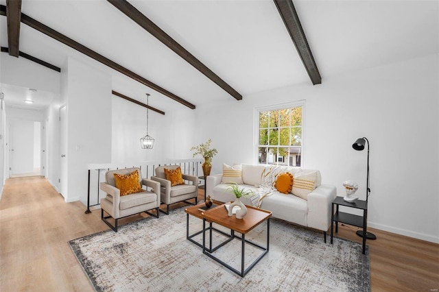 living room with light hardwood / wood-style flooring, lofted ceiling with beams, and a notable chandelier