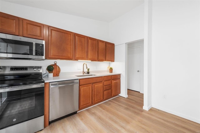 kitchen with vaulted ceiling, sink, stainless steel appliances, and light hardwood / wood-style flooring