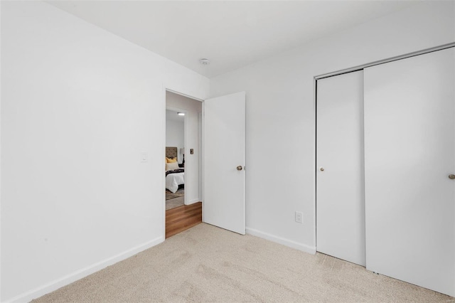 unfurnished bedroom featuring light carpet and a closet