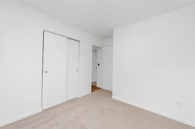 unfurnished bedroom featuring light colored carpet and a closet