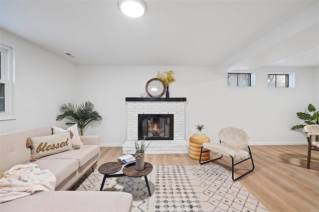 living room with a brick fireplace and light hardwood / wood-style flooring