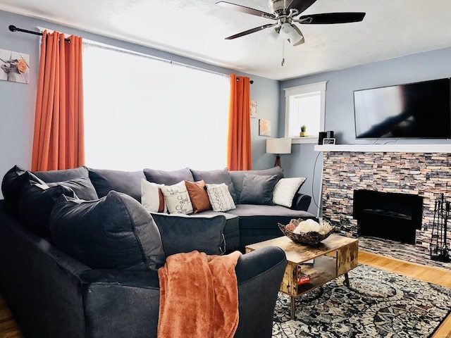 living room featuring ceiling fan, a fireplace, and wood-type flooring