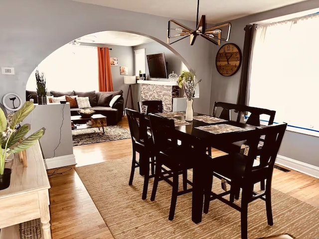 dining space with a chandelier, wood-type flooring, and a fireplace