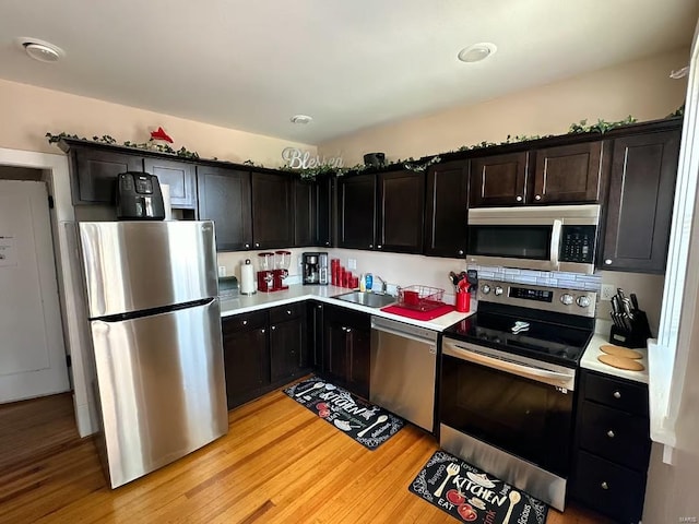 kitchen with appliances with stainless steel finishes, light hardwood / wood-style flooring, and sink