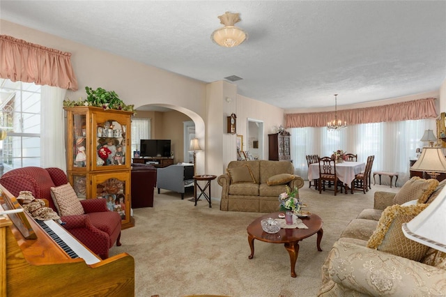 carpeted living room with a textured ceiling and a notable chandelier