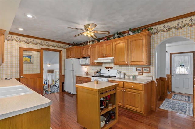 kitchen featuring a kitchen island, white appliances, dark wood-type flooring, and ornamental molding