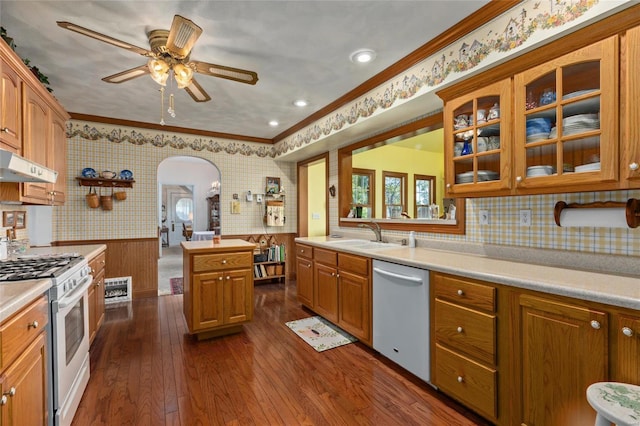 kitchen featuring stainless steel dishwasher, ornamental molding, gas range, dark wood-type flooring, and sink