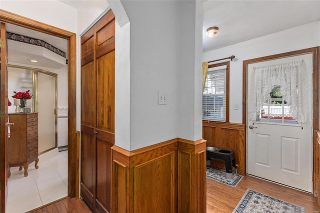 foyer entrance with wood walls and light wood-type flooring