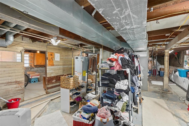 basement featuring gas water heater and wood walls