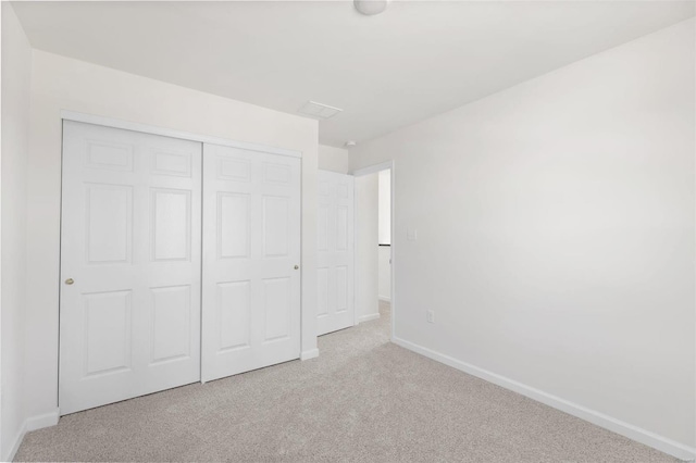 unfurnished bedroom featuring a closet and light colored carpet