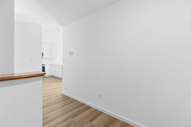 hallway with light hardwood / wood-style floors and lofted ceiling