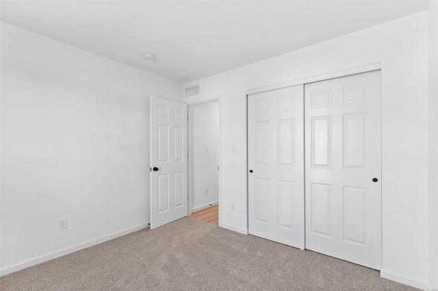 unfurnished bedroom featuring light colored carpet and a closet