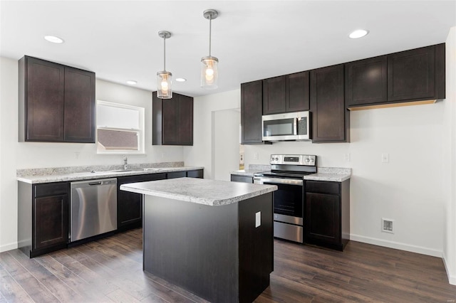 kitchen featuring a kitchen island, dark wood-type flooring, decorative light fixtures, and appliances with stainless steel finishes