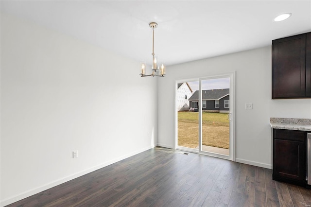 unfurnished dining area with dark hardwood / wood-style floors and an inviting chandelier