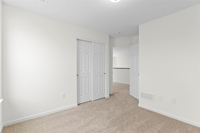 unfurnished bedroom featuring light colored carpet and a closet