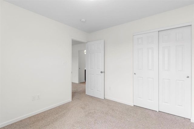 unfurnished bedroom featuring light colored carpet and a closet