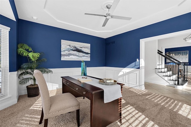 carpeted home office with visible vents, a ceiling fan, and wainscoting