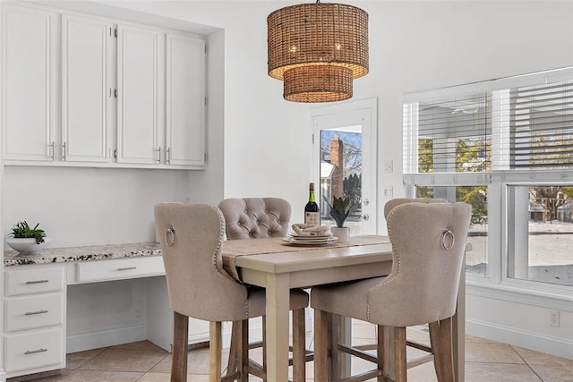 dining area featuring light tile patterned flooring, baseboards, a chandelier, and built in study area