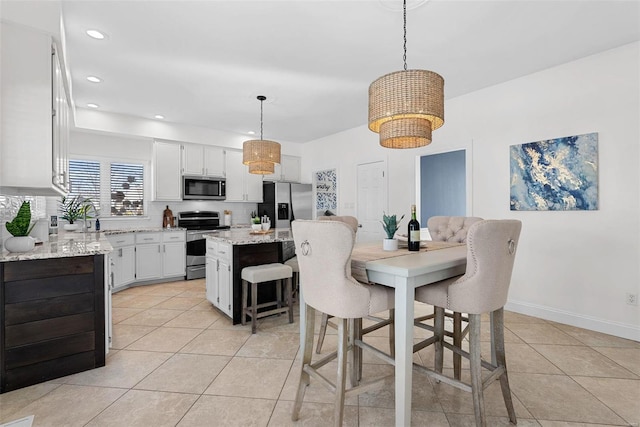 kitchen featuring light tile patterned flooring, a sink, hanging light fixtures, stainless steel appliances, and a center island