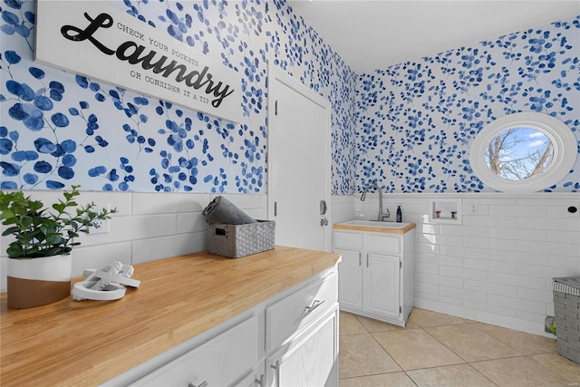 bathroom with a sink, a wainscoted wall, tile patterned floors, and wallpapered walls