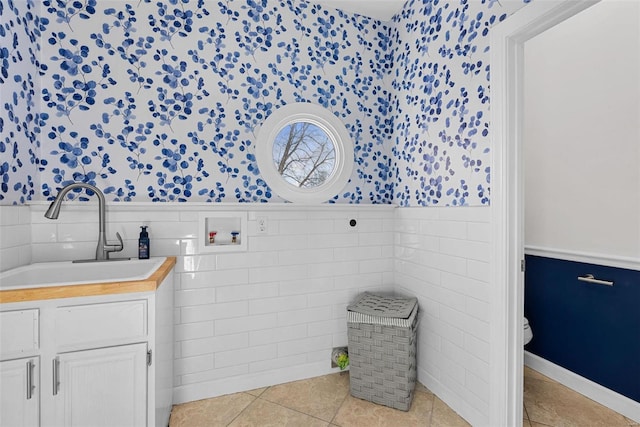 bathroom with vanity, a wainscoted wall, wallpapered walls, tile patterned floors, and toilet