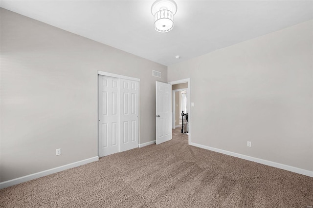 unfurnished bedroom featuring visible vents, carpet flooring, baseboards, and a closet