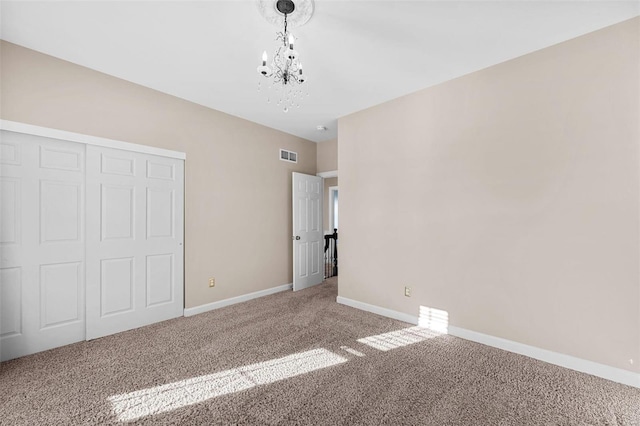 unfurnished bedroom with visible vents, baseboards, carpet floors, a closet, and a notable chandelier