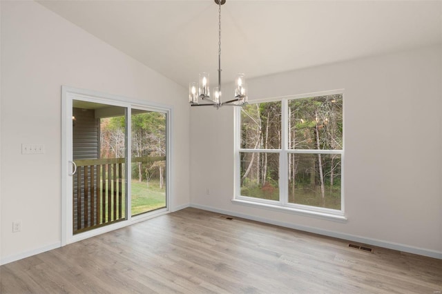 unfurnished dining area featuring light hardwood / wood-style flooring, a chandelier, and lofted ceiling