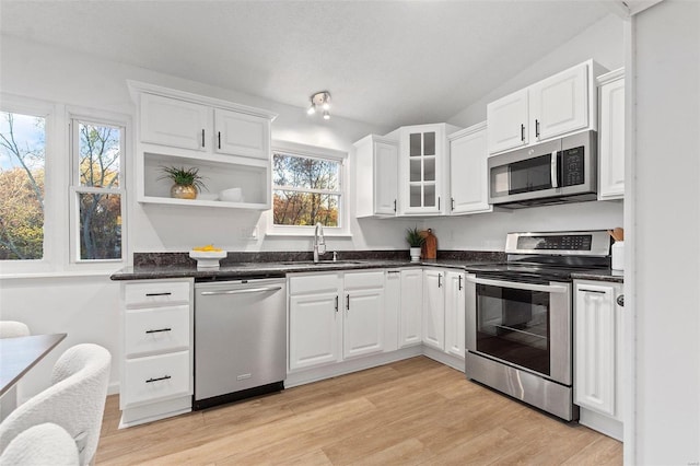 kitchen featuring a wealth of natural light, appliances with stainless steel finishes, white cabinetry, sink, and light hardwood / wood-style flooring