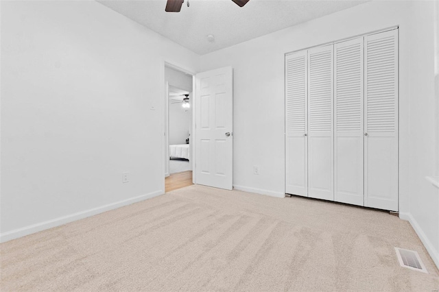 unfurnished bedroom with ceiling fan, a closet, and light carpet