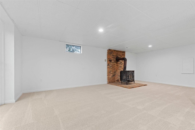 unfurnished living room featuring a wood stove and carpet flooring