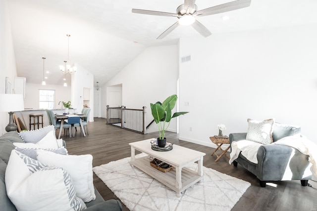 living room with ceiling fan with notable chandelier, hardwood / wood-style flooring, and high vaulted ceiling