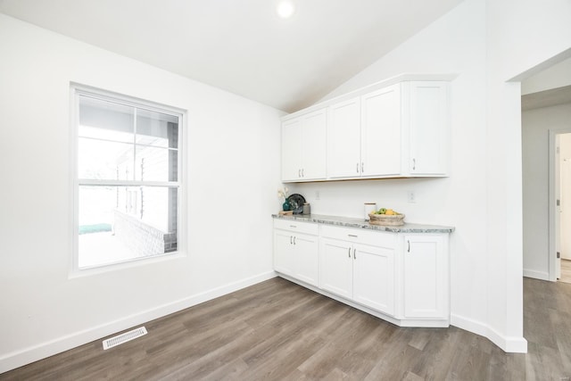 bar featuring white cabinets, light stone countertops, hardwood / wood-style flooring, and vaulted ceiling