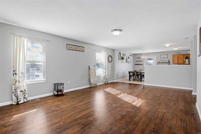 unfurnished living room with dark hardwood / wood-style flooring and an inviting chandelier