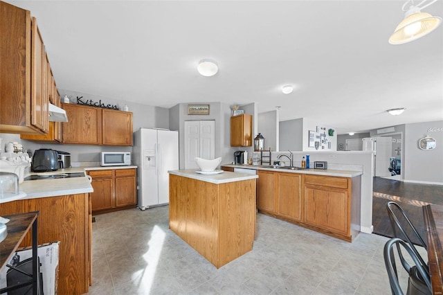 kitchen featuring a center island, white appliances, sink, hanging light fixtures, and kitchen peninsula